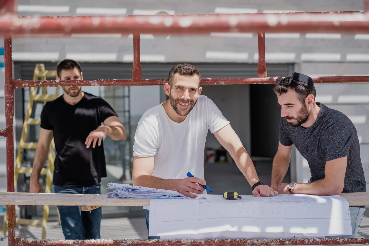 צוות עוז הנדסה בוחן תוכניות בנייה מבעד לפיגום באתר